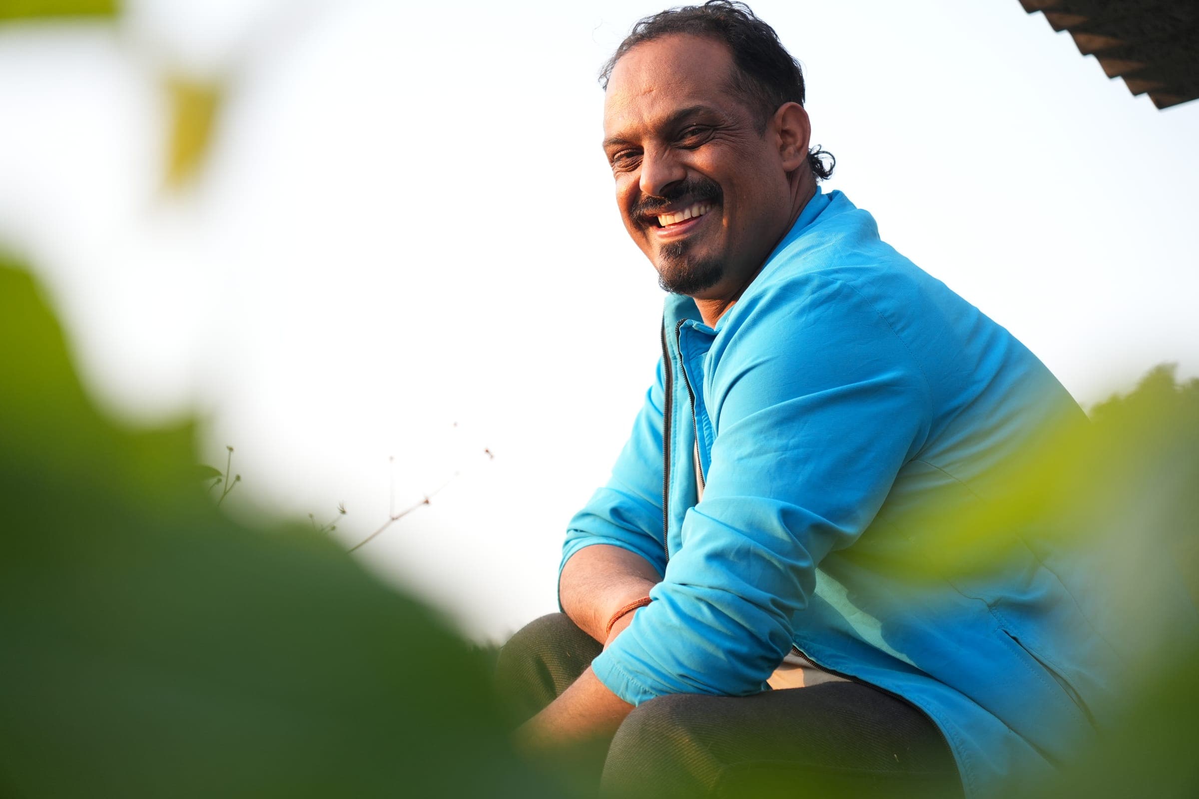 A man in a blue jacket smiling among the leaves