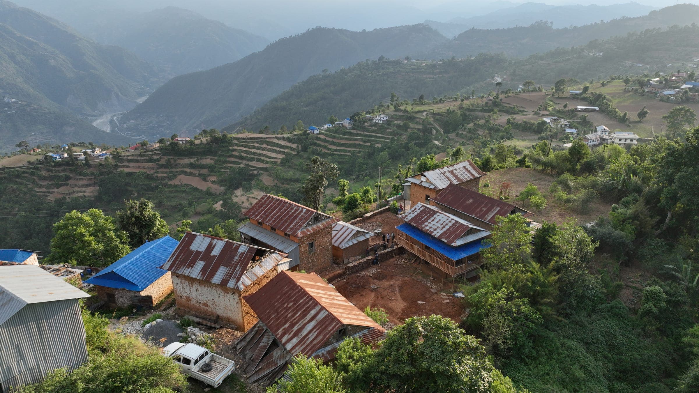 Thumka's stone houses and the new courtyard in the evening light, with the river valley behind