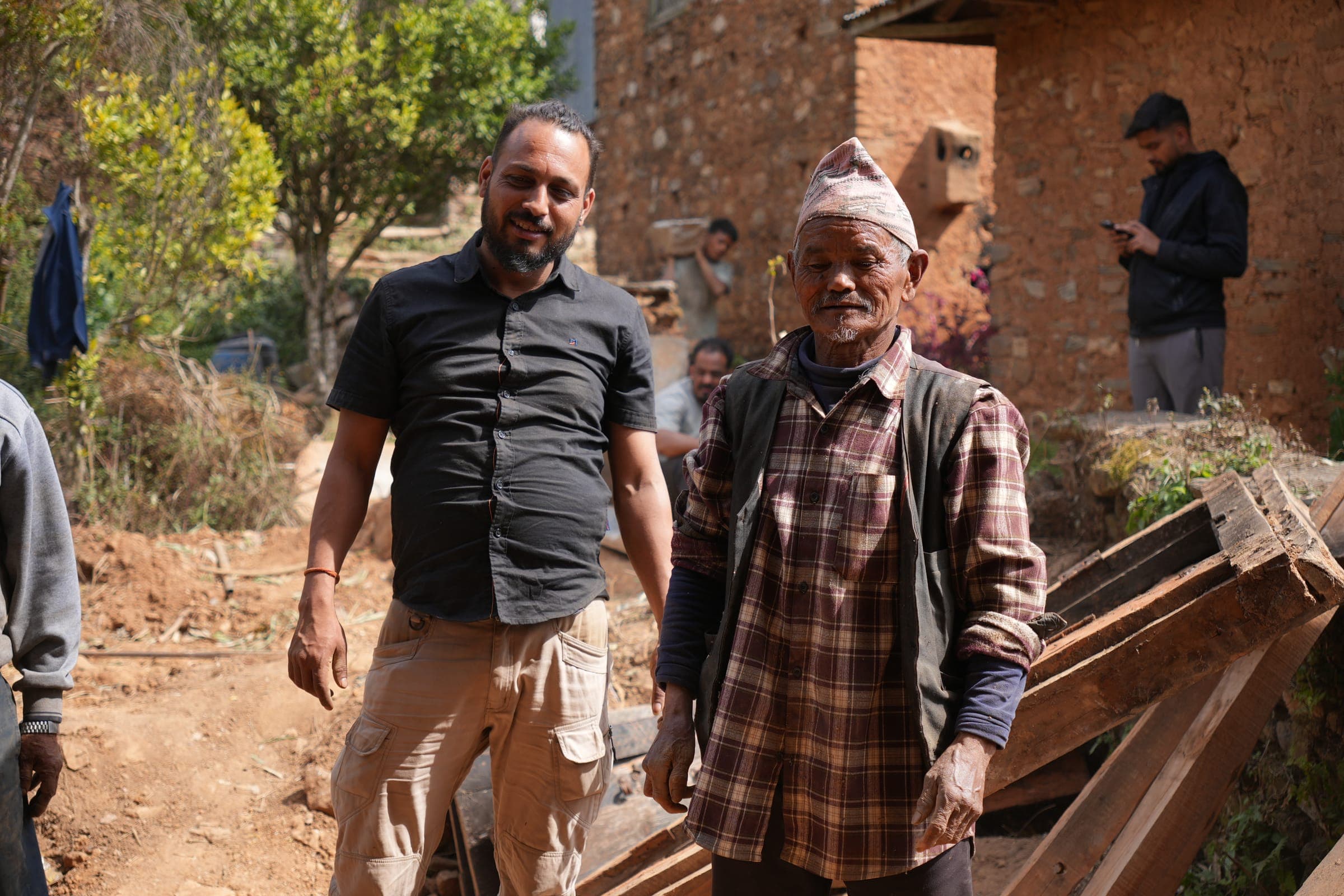 Two men from the village laughing together in front of a stone house